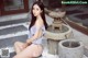 A woman sitting on the ground next to a fountain.
